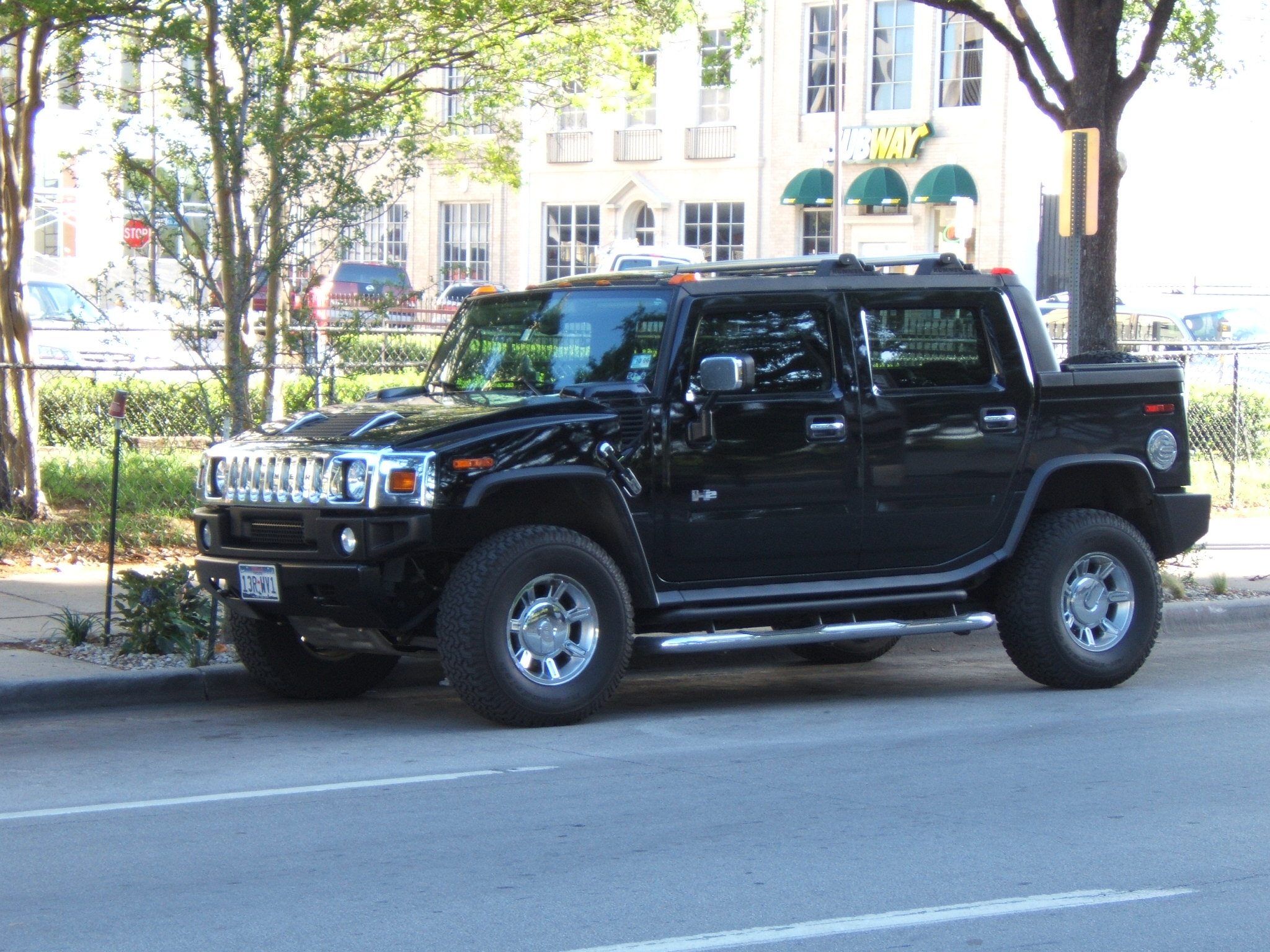 a large suv parked on a street next to a tree