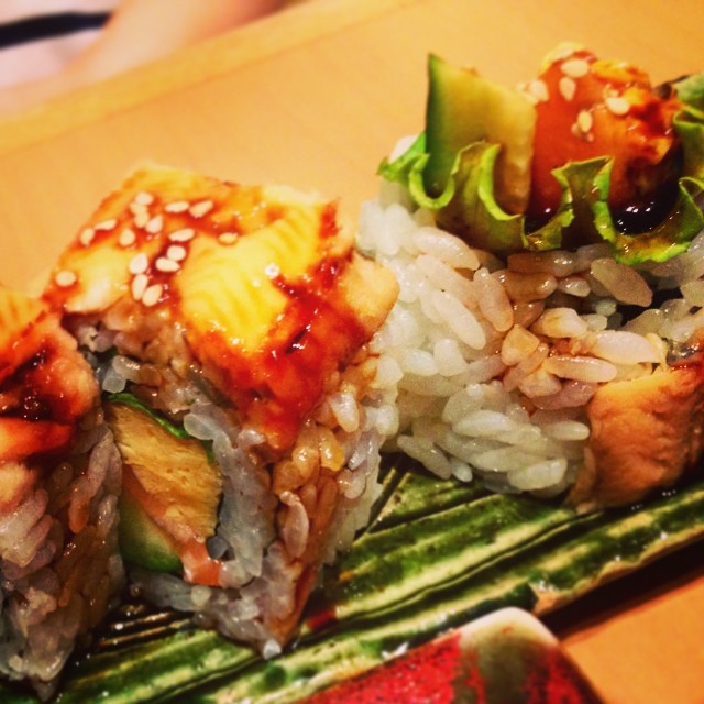 a sushi topped with sesame seed and sauce, sitting on top of rice