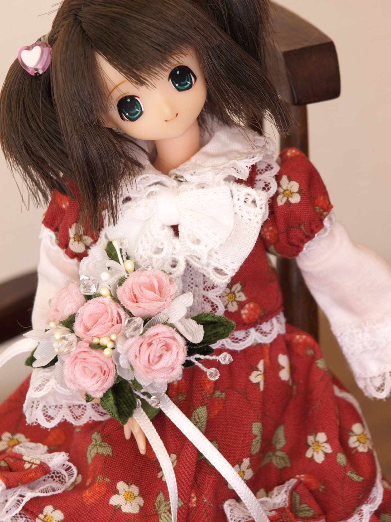 doll sitting on chair with pink flowers and a flower bouquet
