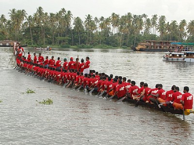 a long boat full of people riding across a lake