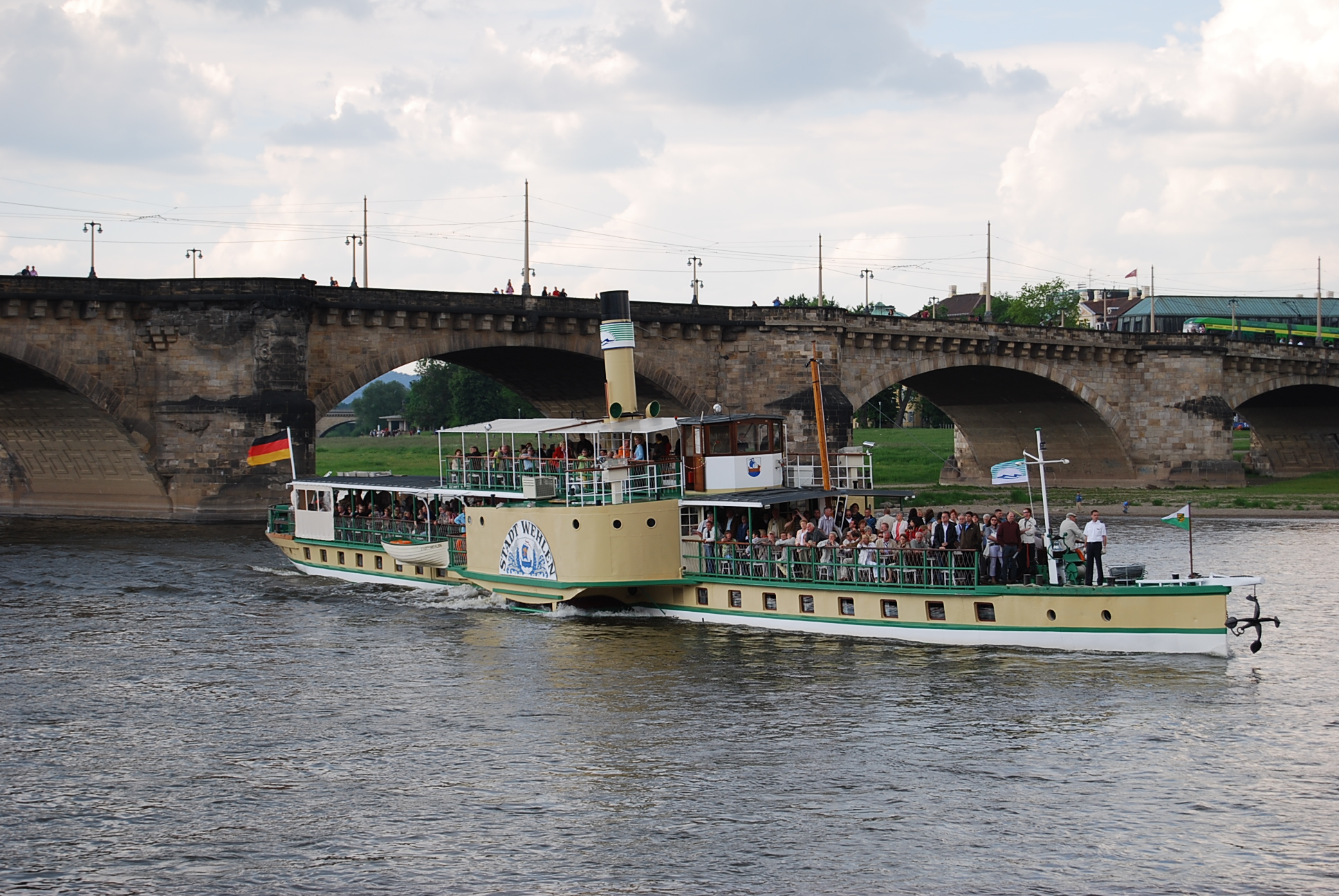 a large passenger boat on a river next to a bridge