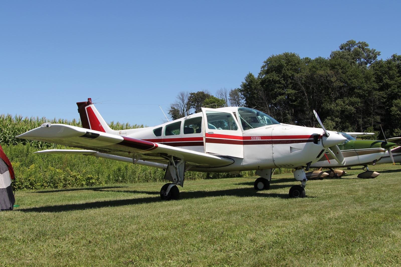 a white plane on a grassy field with some trees in the background