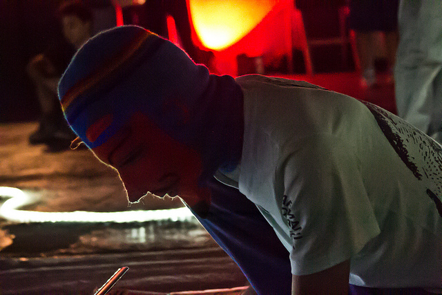 a man wearing a beanie sitting in front of an oven