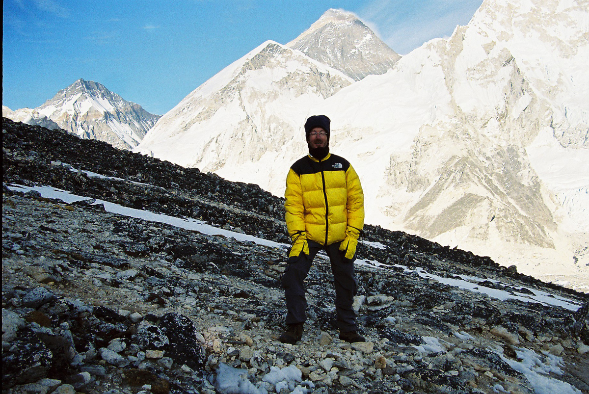 a person on a rocky hill with mountains in the background