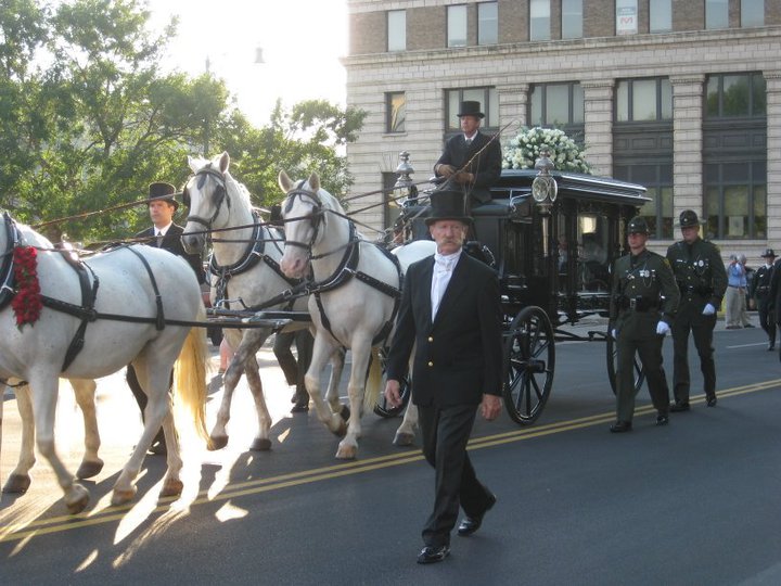 men in uniform in a horse drawn carriage in the street