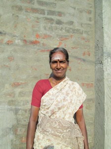a woman in a white and beige sari smiles in an alley