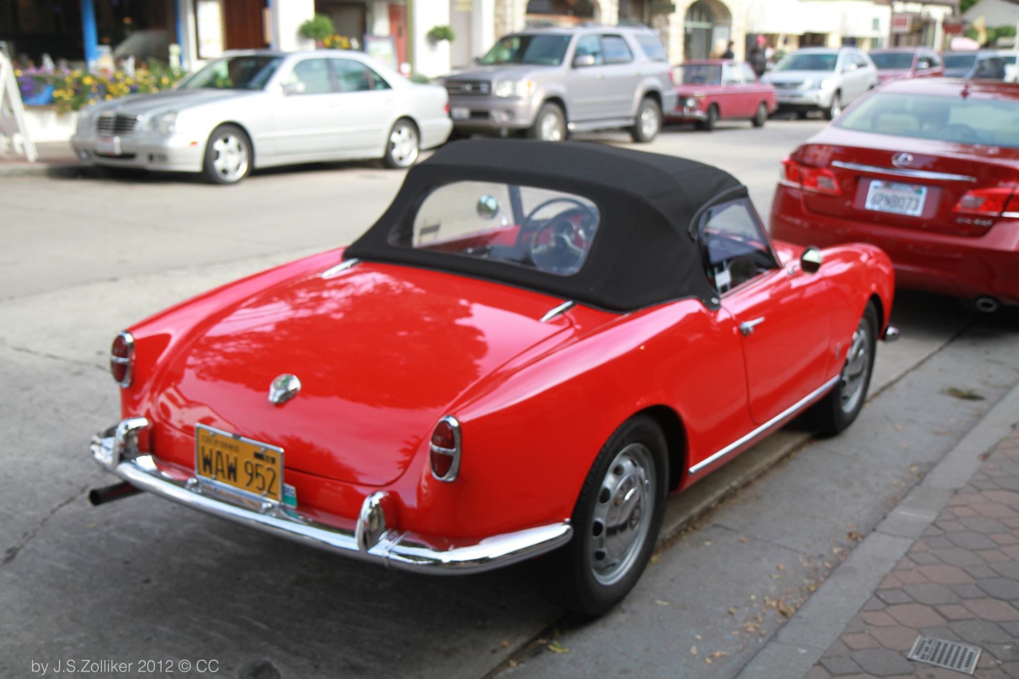 a bright red sports car is parked in the street