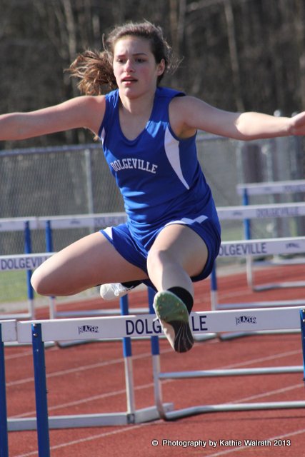 a young woman jumping over a hurdle in a track