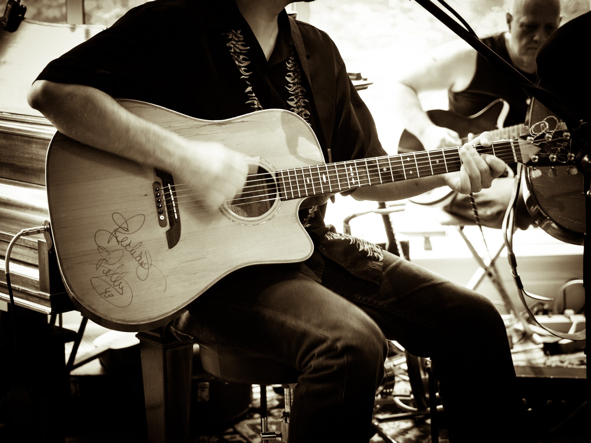 a person sitting in front of a microphone while playing a guitar