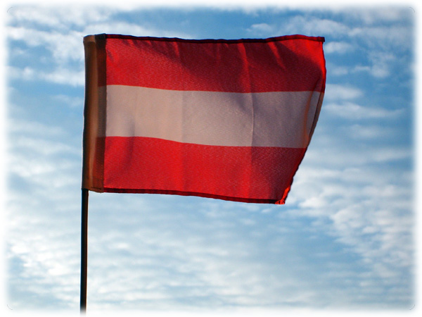 a large red and white flag with blue skies in the background