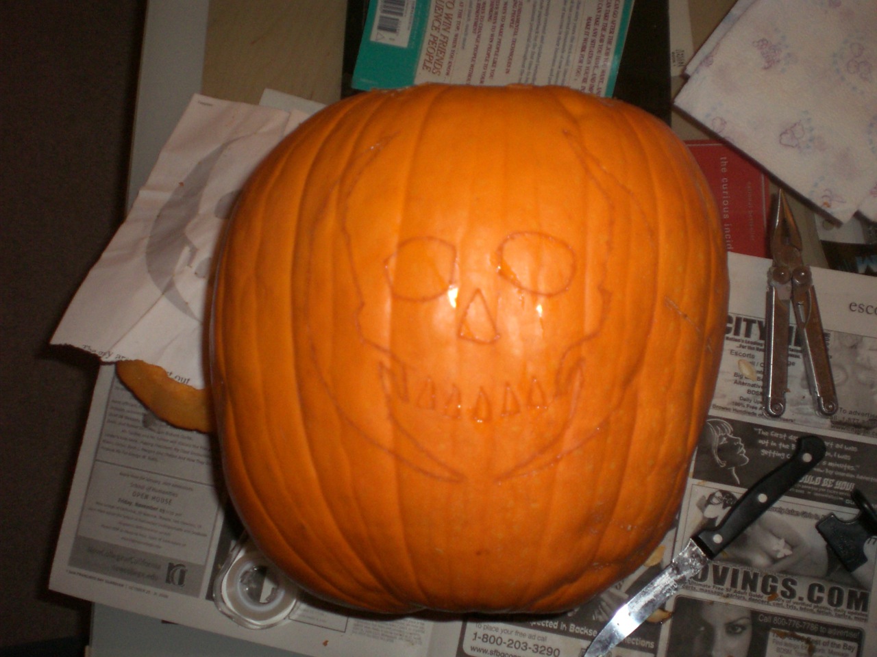 a pumpkin with a face carved on it sitting next to scissors