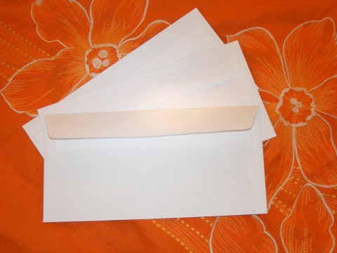 three pieces of white envelope sitting on a bed with flowers