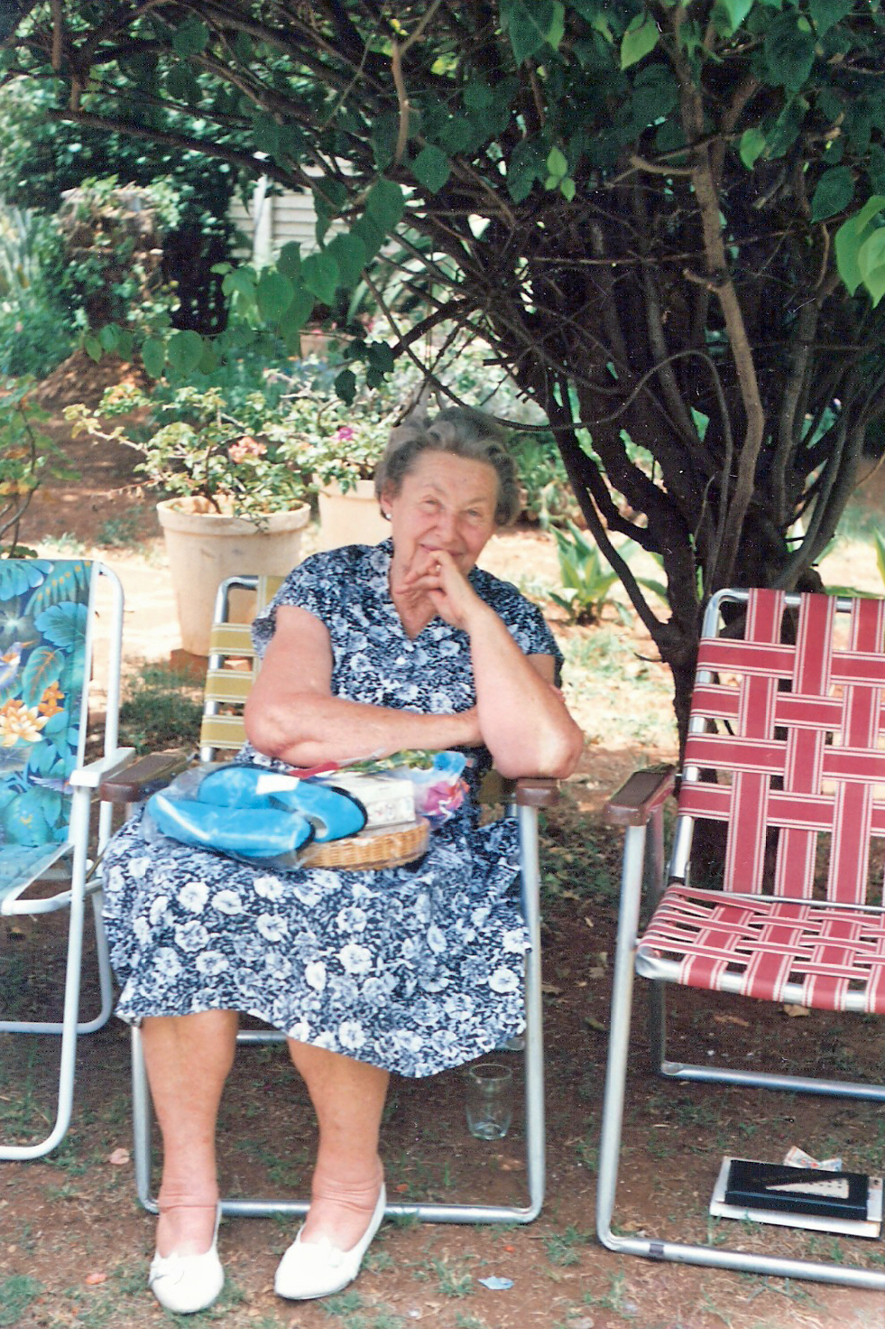 a very old lady sitting in a chair under a tree