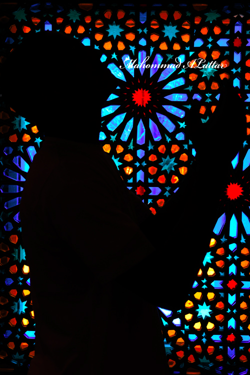 silhouetted person with cellphone against multicolored stained glass