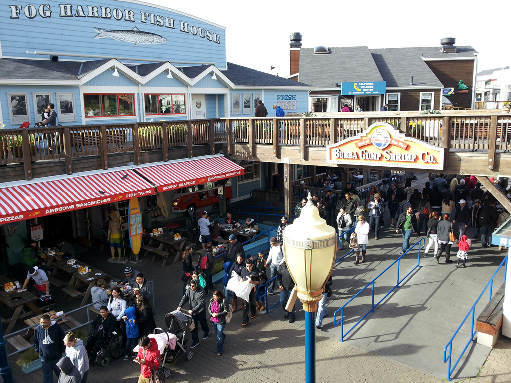 people walk in a town center next to the boardwalk