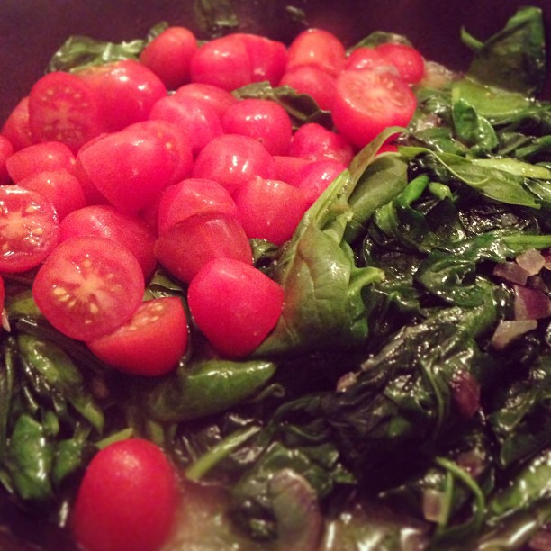 a salad with spinach, tomatoes and onions