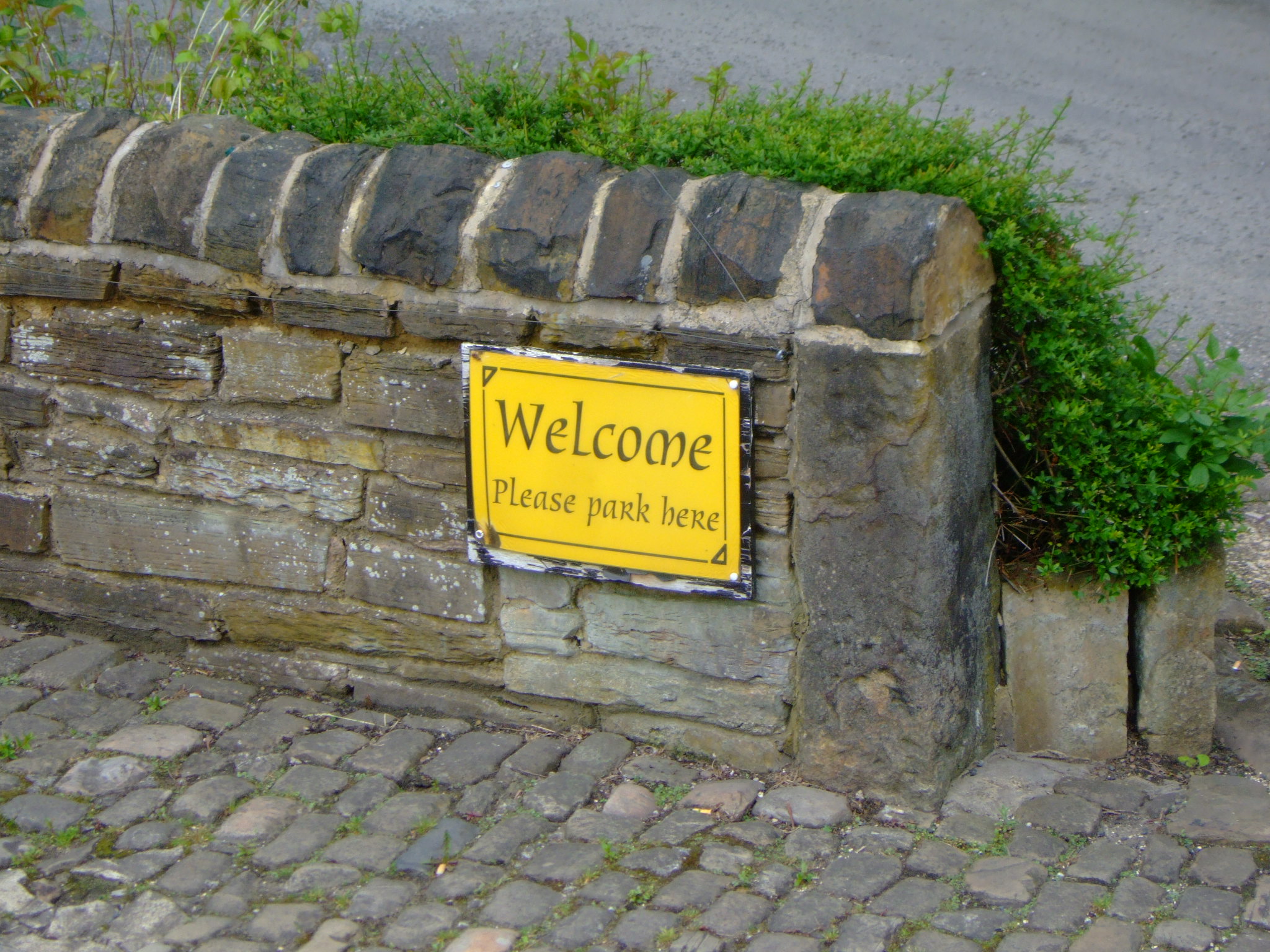 there is a welcome sign by a stone wall