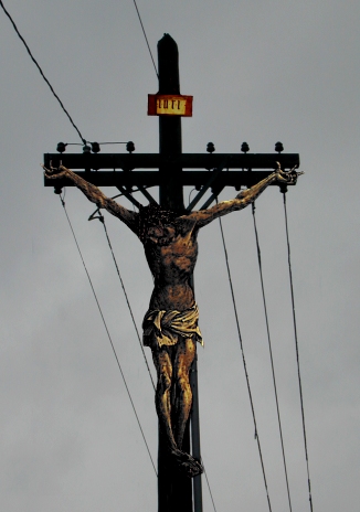 a crucifix on a black pole in the street