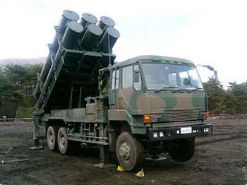 a camouflage camo army truck with many metal objects on the bed
