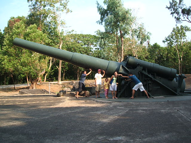 four people are standing next to a large, metal cannon