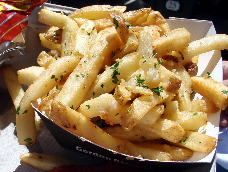 a close up of a tray of fries with parsley on top
