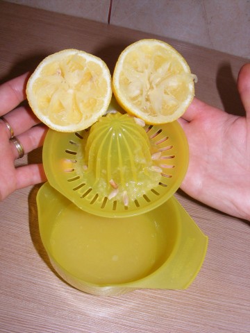 the hand is holding a yellow lemon fruit slicer