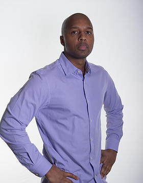 a man wearing a purple shirt standing with his hands on his hips