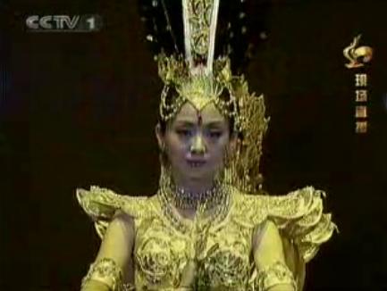 a woman wearing elaborate clothing and headpieces standing on stage