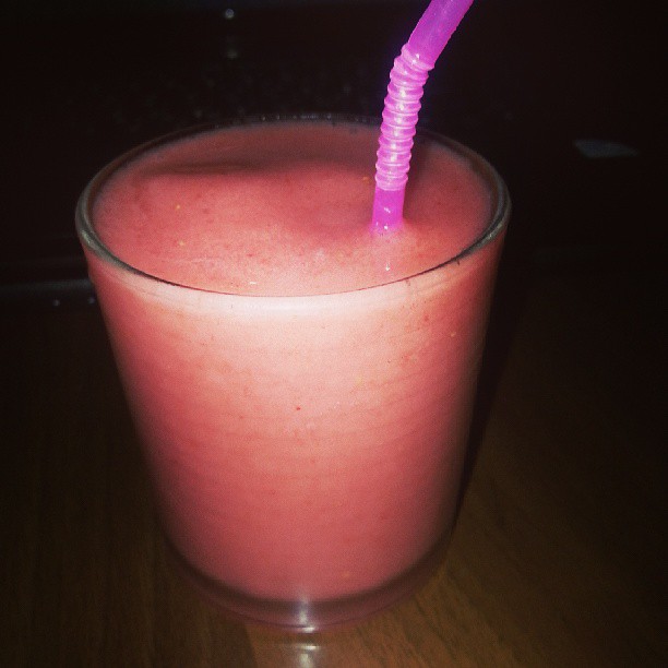 a pink drink in a glass with purple straws
