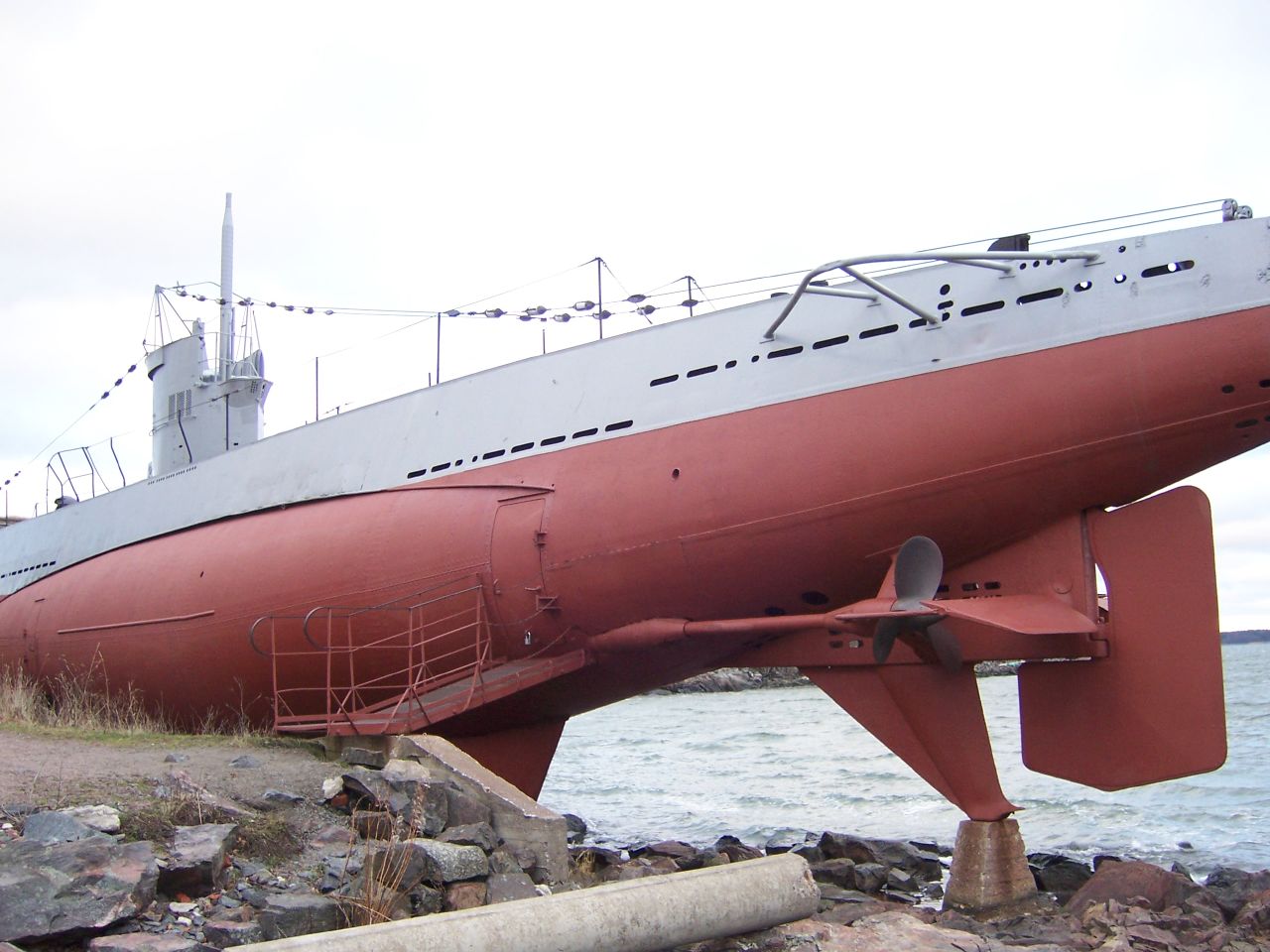 an old red boat sitting on some rocks