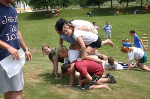 a group of children and adults playing tug of war in the park