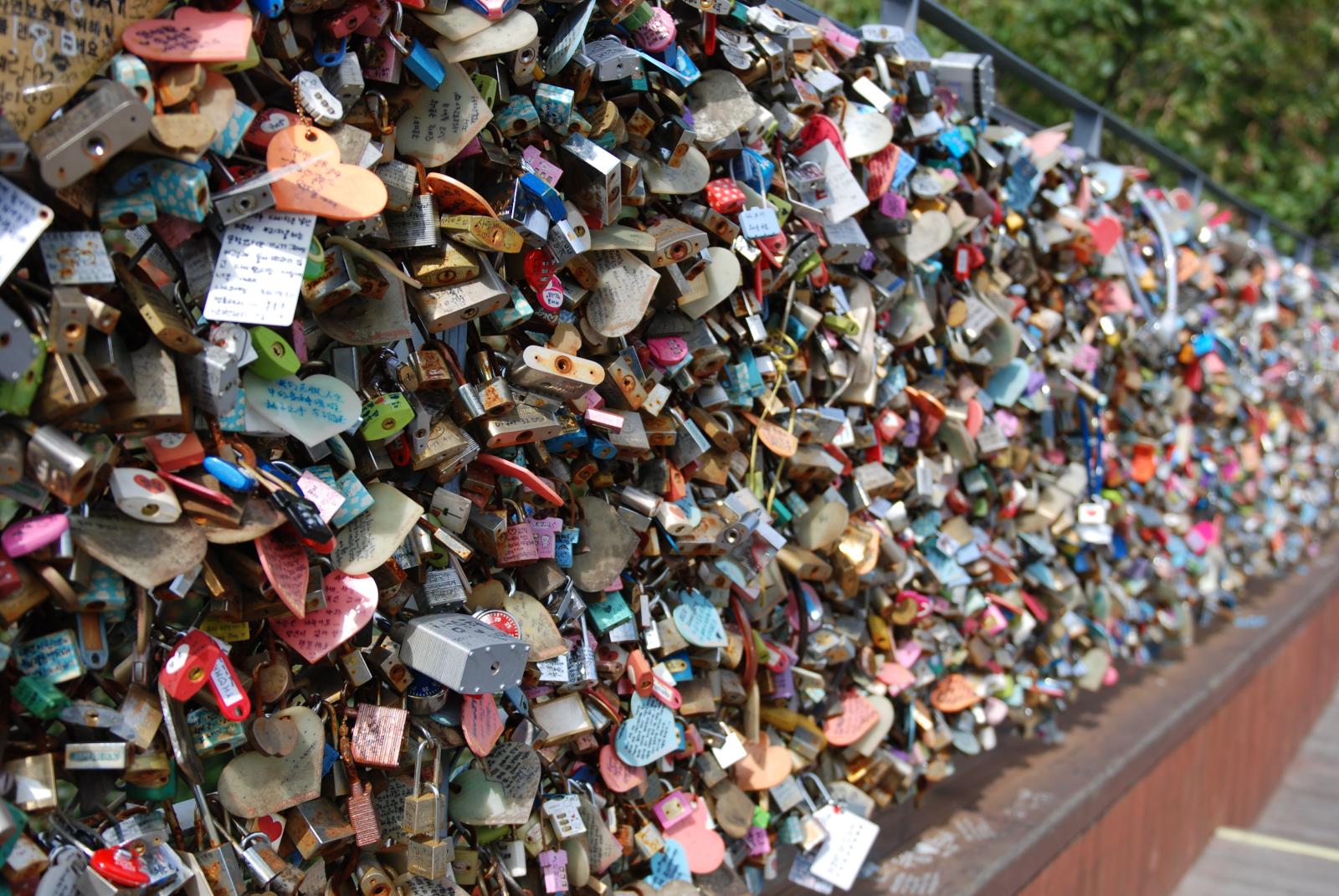 love locks and padlocks attached to a wall