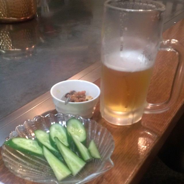 a plate of cucumber slices next to a mug of beer