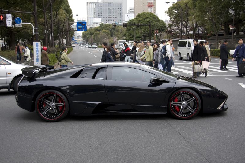 black sports car driving down the street at a busy intersection