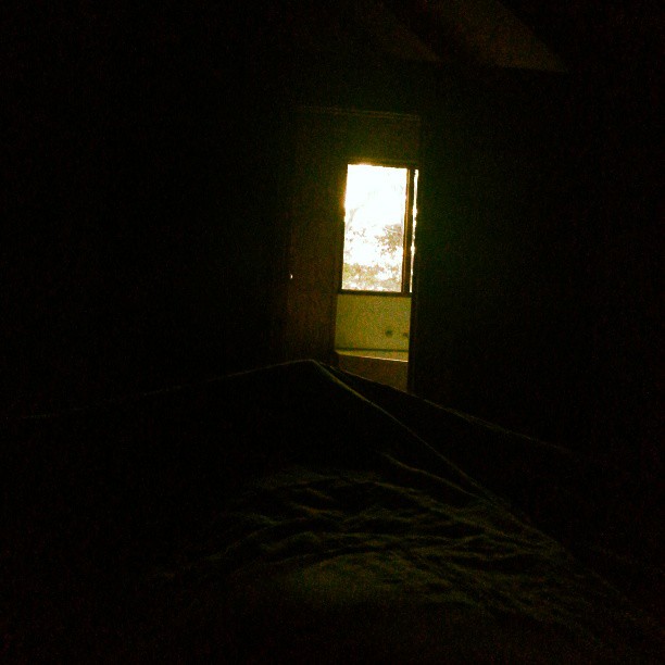 an open bed in a dark room with a window