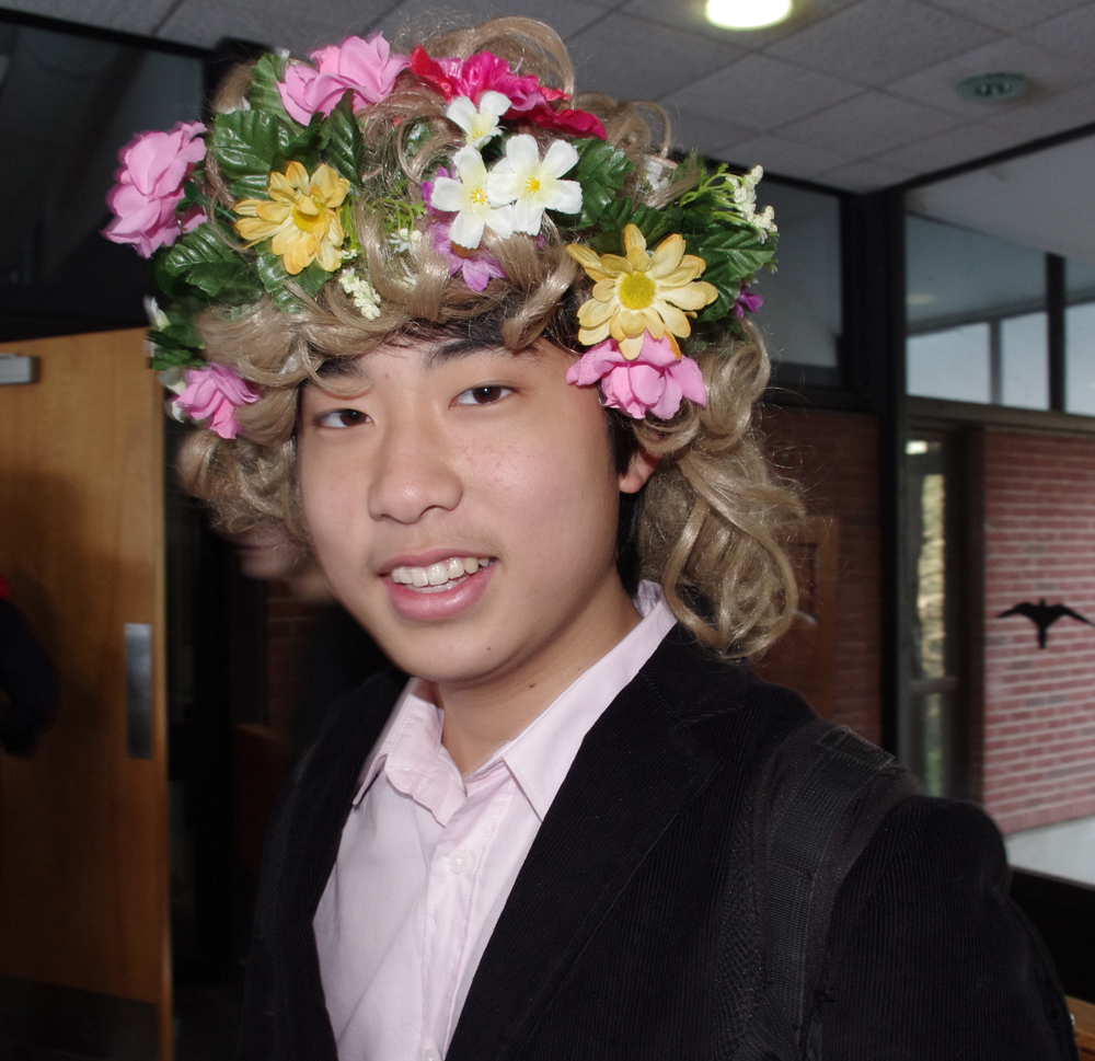 a man wearing a flower crown with another person in the background