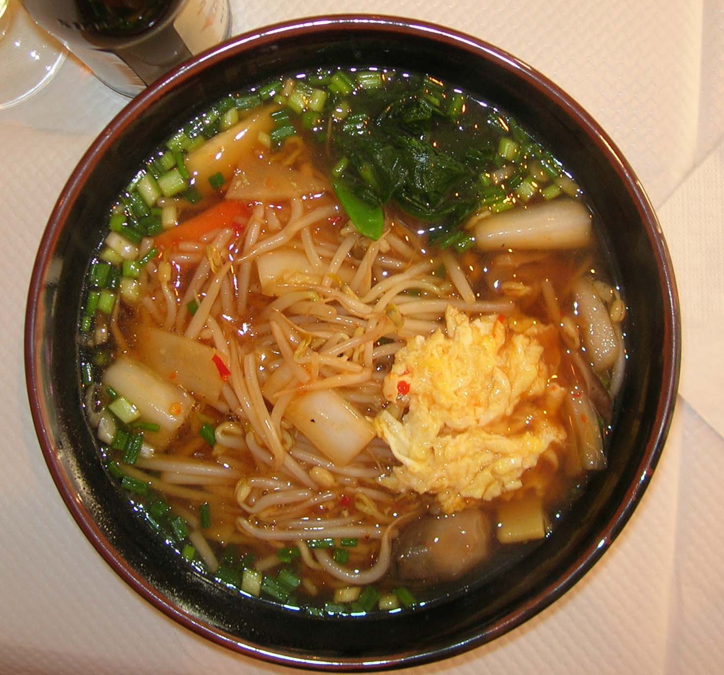 a bowl of noodles and vegetables with chopsticks