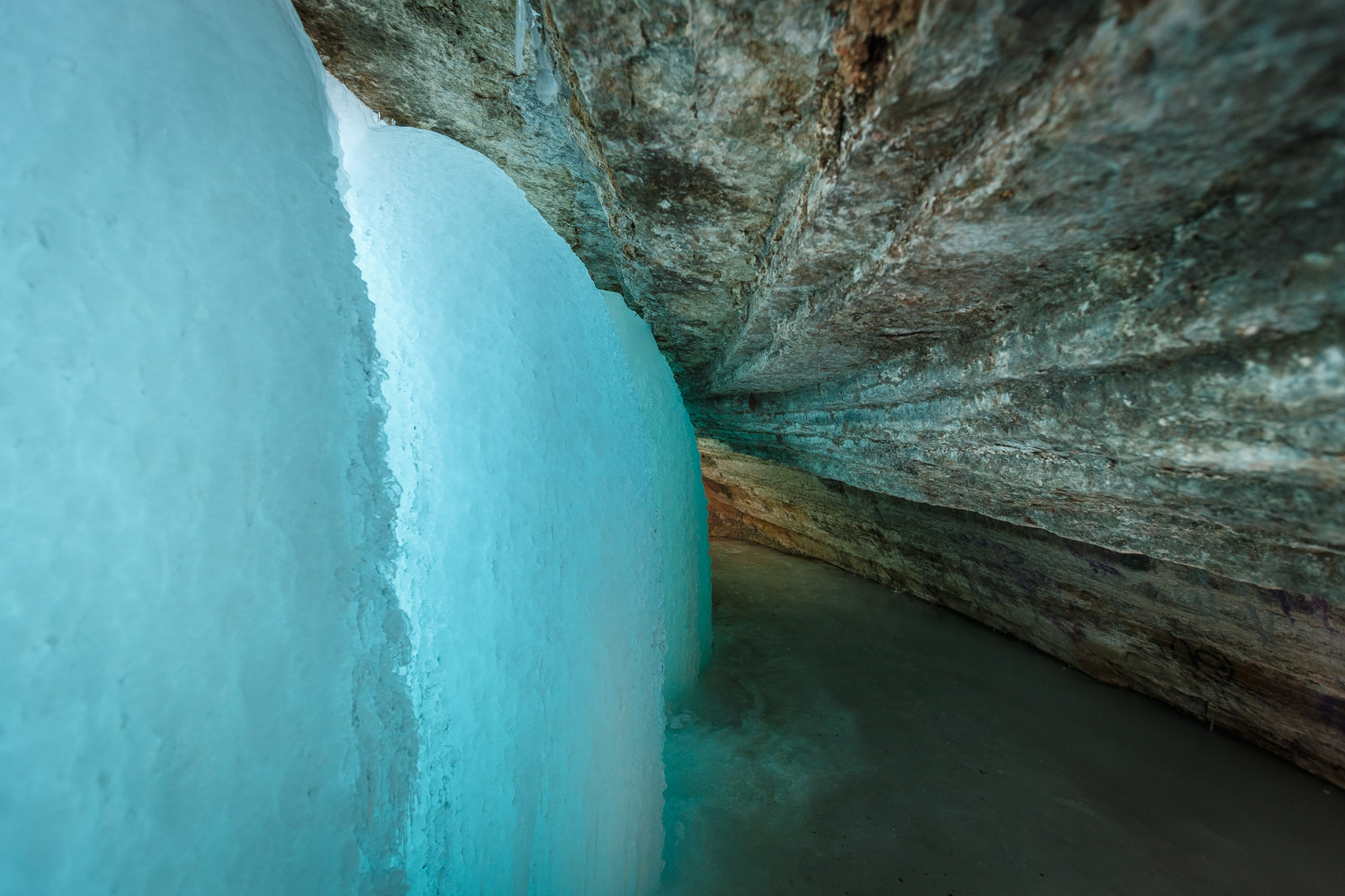 there are ice formations growing on the sides of the walls of this cave