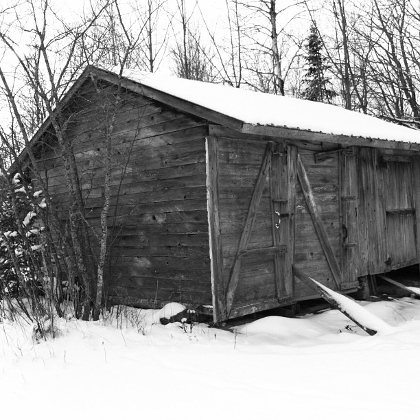 an old rustic wood shed sitting in the middle of the snow