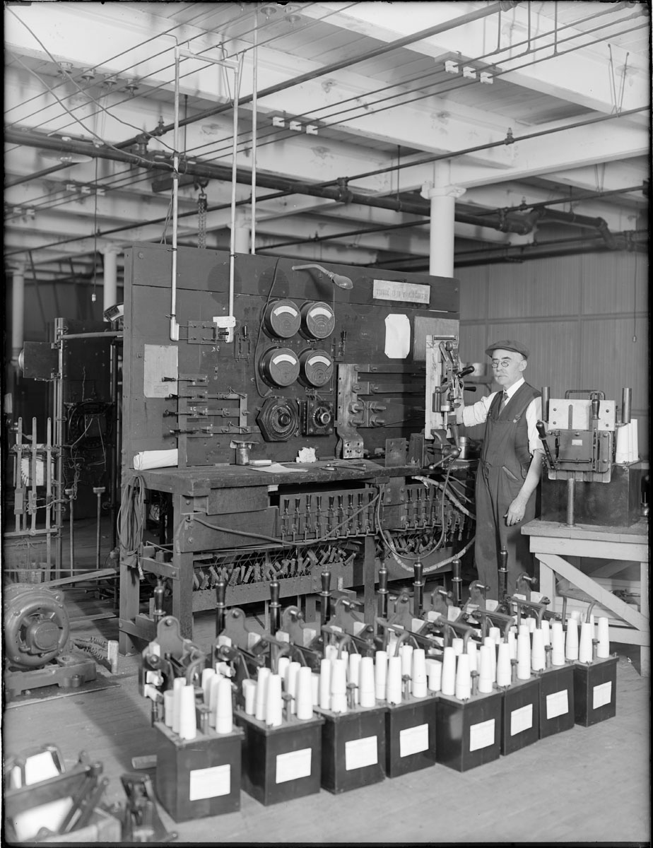 a man standing by a machine with lots of things on it