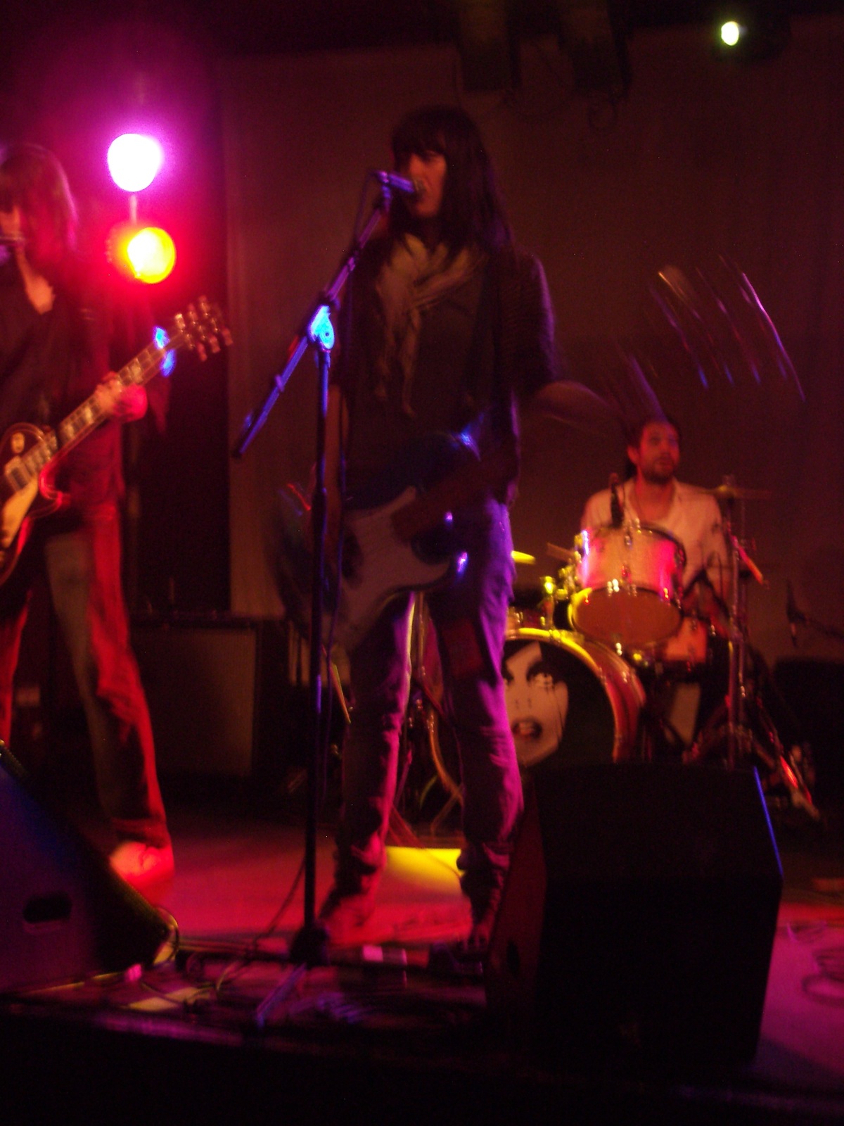 a person playing guitar in front of two other musicians