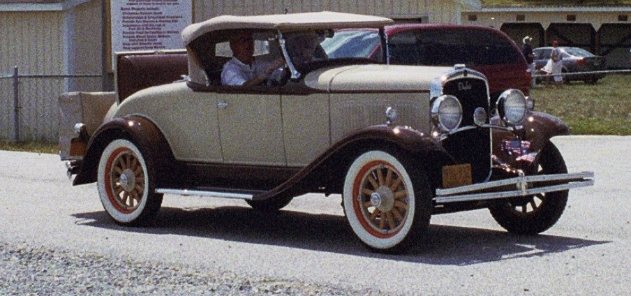 an antique car is shown with others in the background