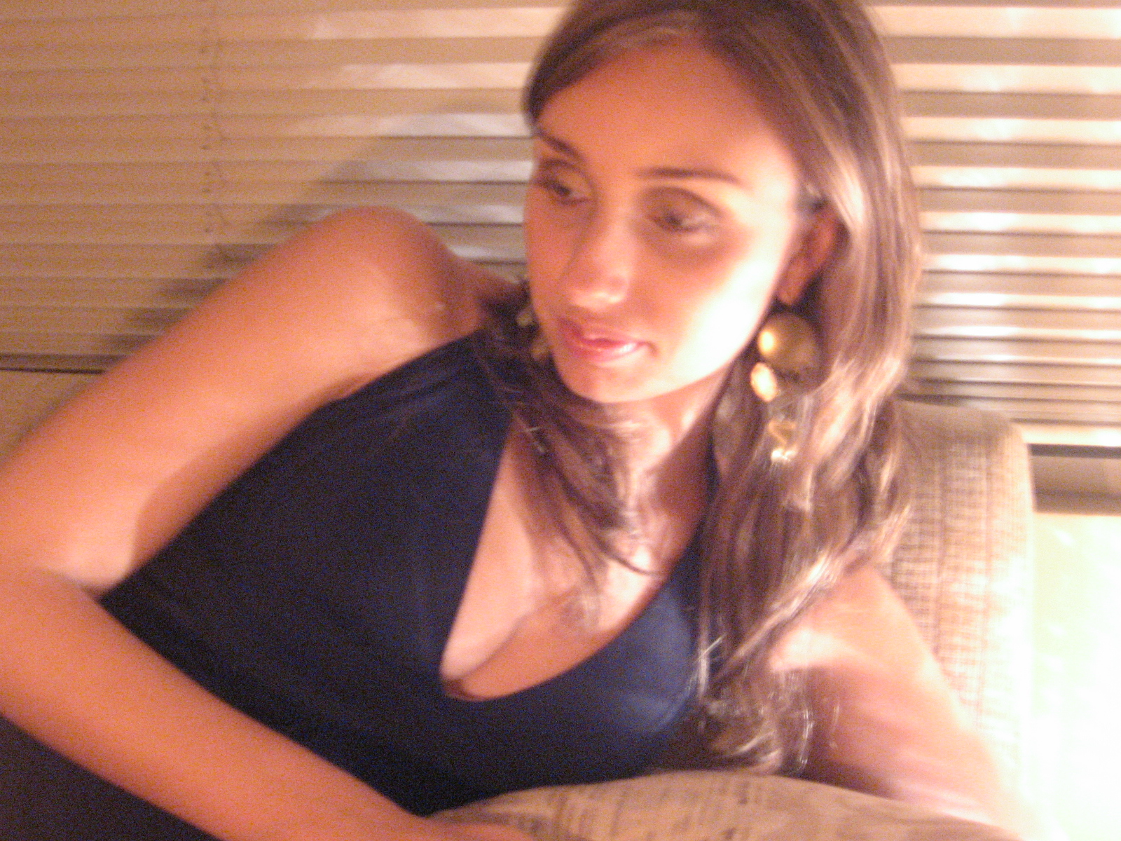 a woman wearing earrings sits in front of a window