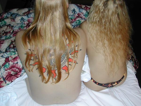 two young women with very long blonde hair on a bed