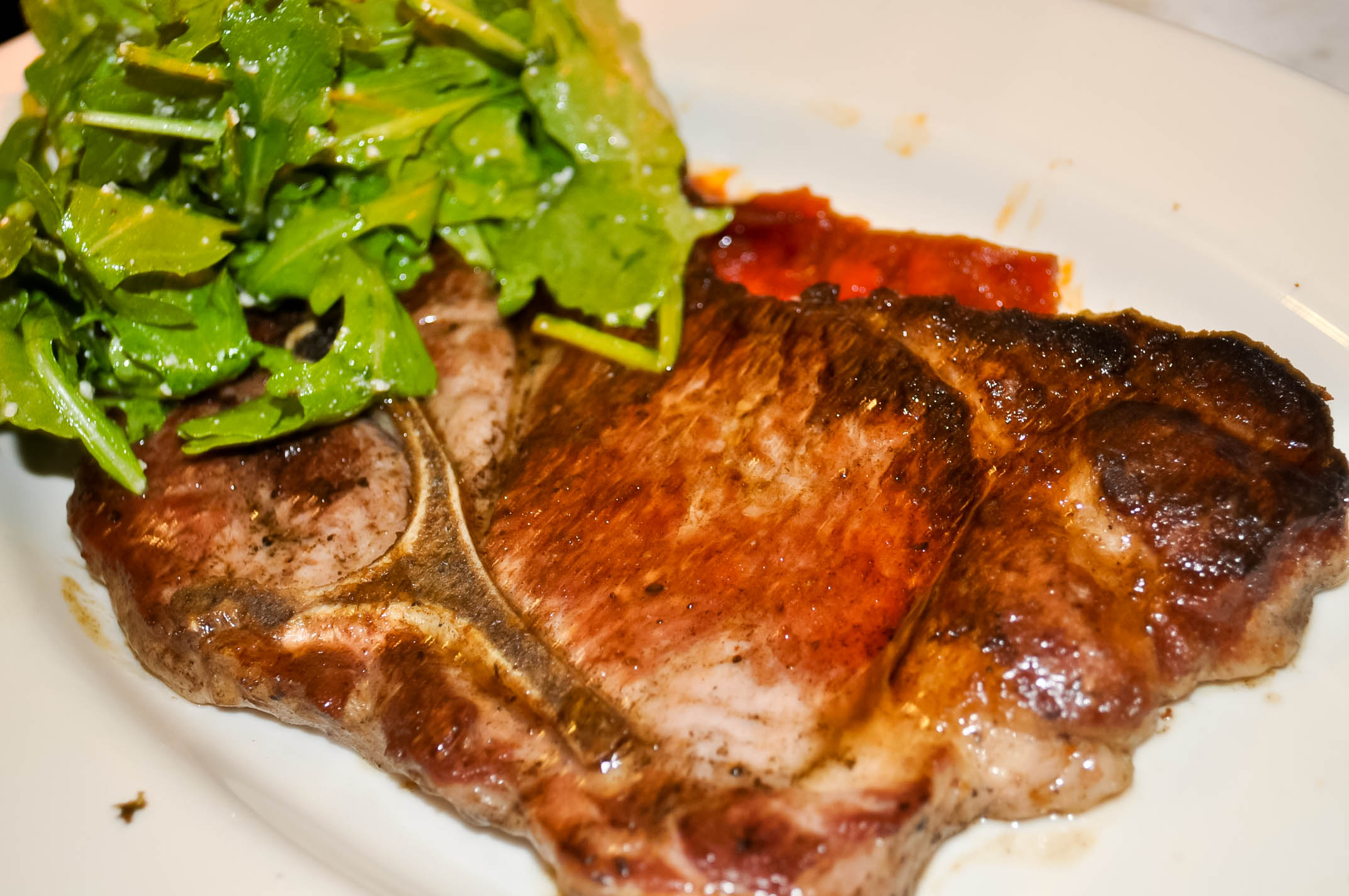 a piece of meat, salad and some veggies on a white plate