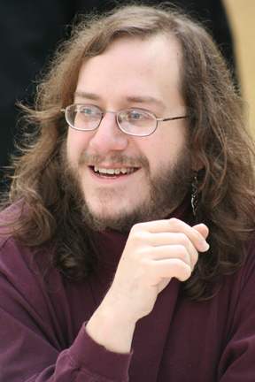a man wearing glasses and smiling for the camera