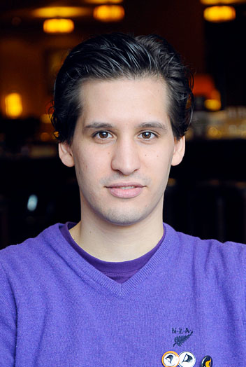 man with dark hair in purple shirt posing for a picture