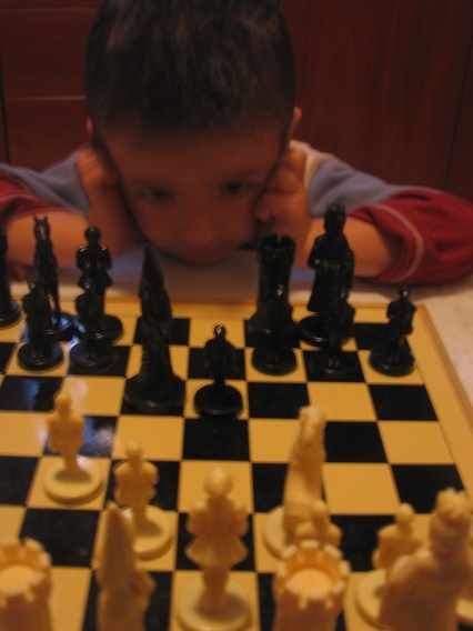 a child playing chess while he has a smile