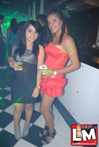 two women in tight dresses holding beverages at an event