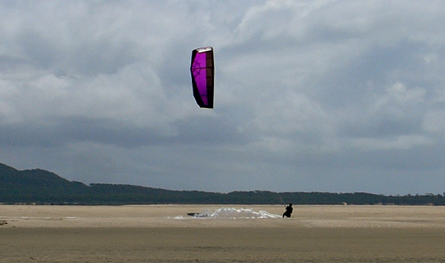 a person who is flying a kite over a beach